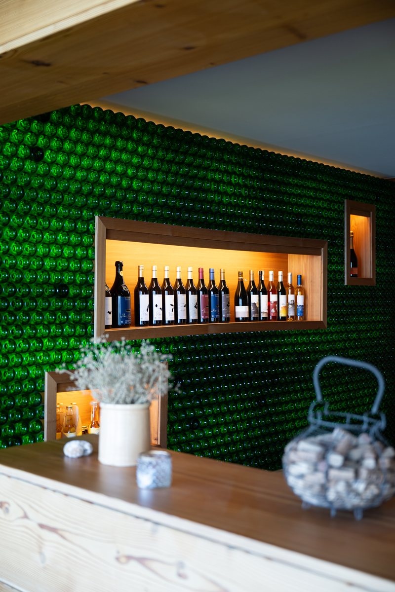 Bouteilles du domaine dans une niche éclairée du mur de bouteilles vertes